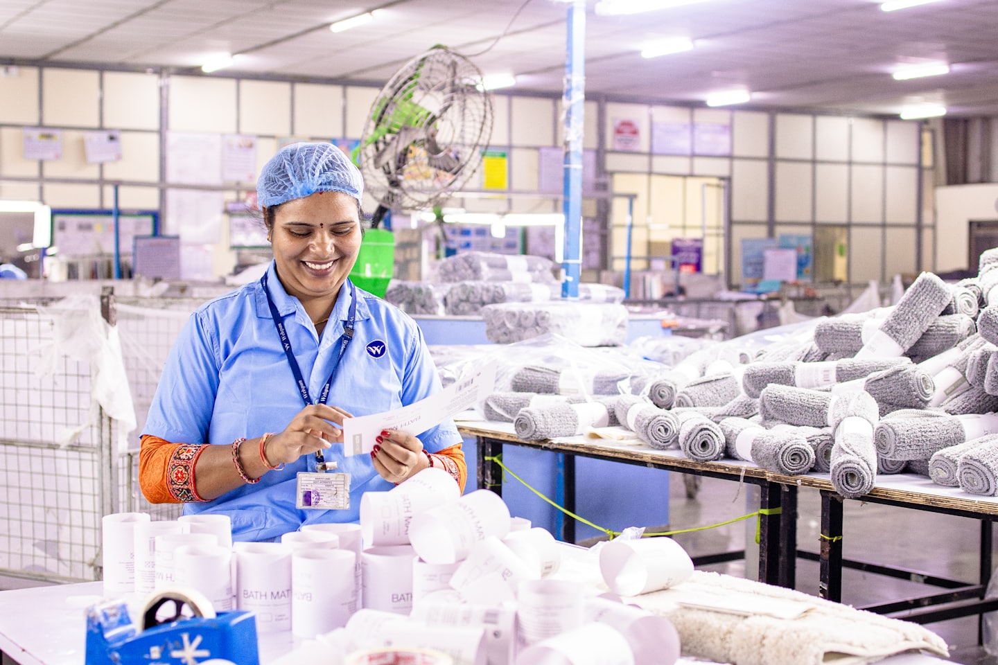 Worker smiling while inspecting a document at a workstation.
