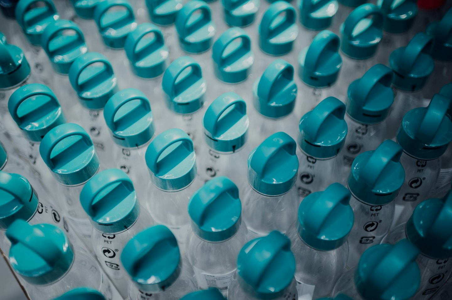 Rows of clear plastic bottles with teal-blue cap handles.