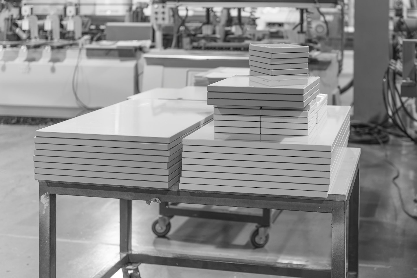 Stacks of white furniture panels rest on a metal cart.